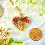 Heart Pendant -- Tiny bouquets of pink flowers set into gold flakes makes for the representation of two cherry trees set into a golden field. Shimmering flecks around the landscape make for a fantasy landscape, somewhere between winter and spring. Made of resin.