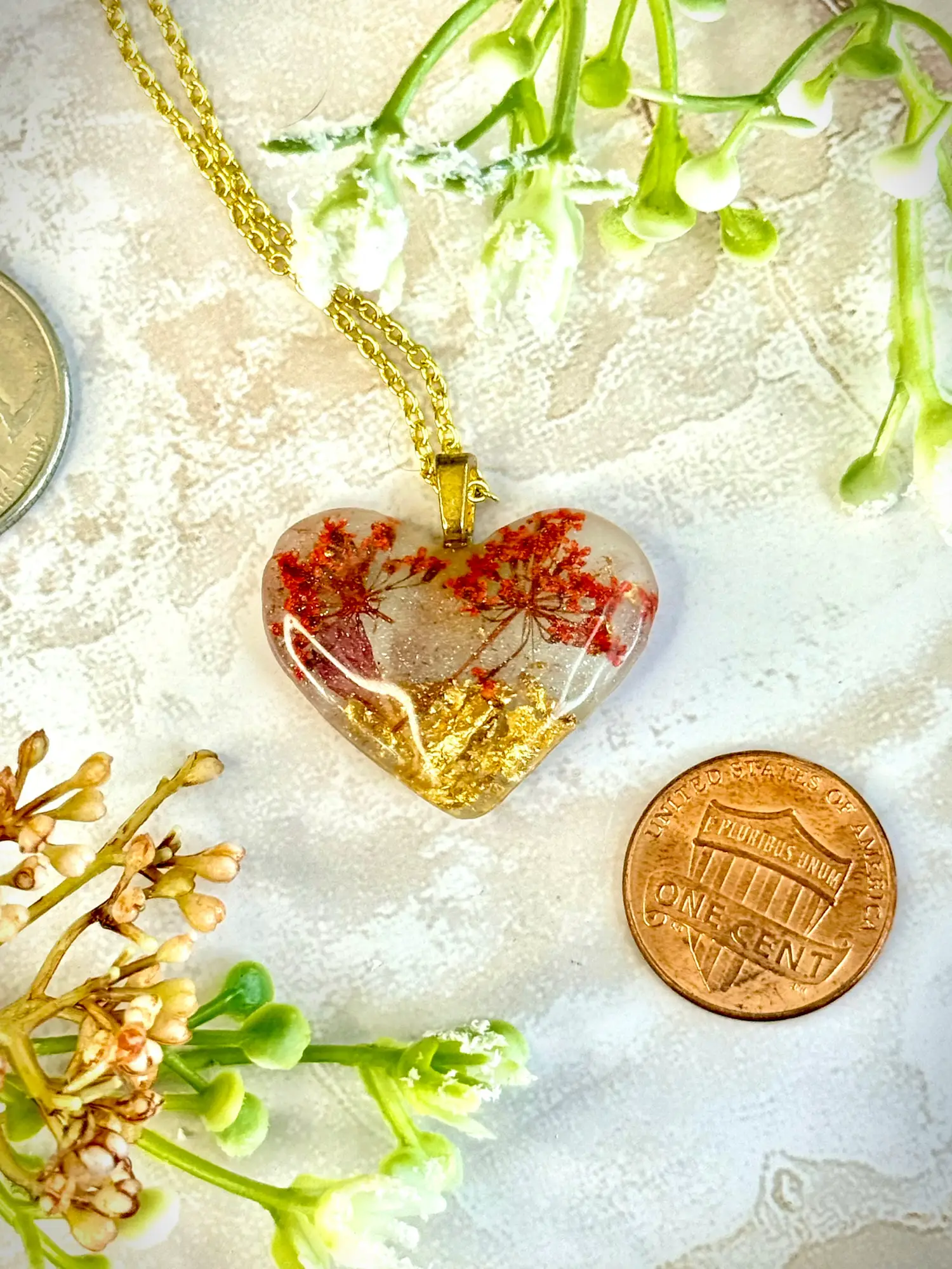 Heart Pendant -- Tiny bouquets of pink flowers set into gold flakes makes for the representation of two cherry trees set into a golden field. Shimmering flecks around the landscape make for a fantasy landscape, somewhere between winter and spring. Made of resin.