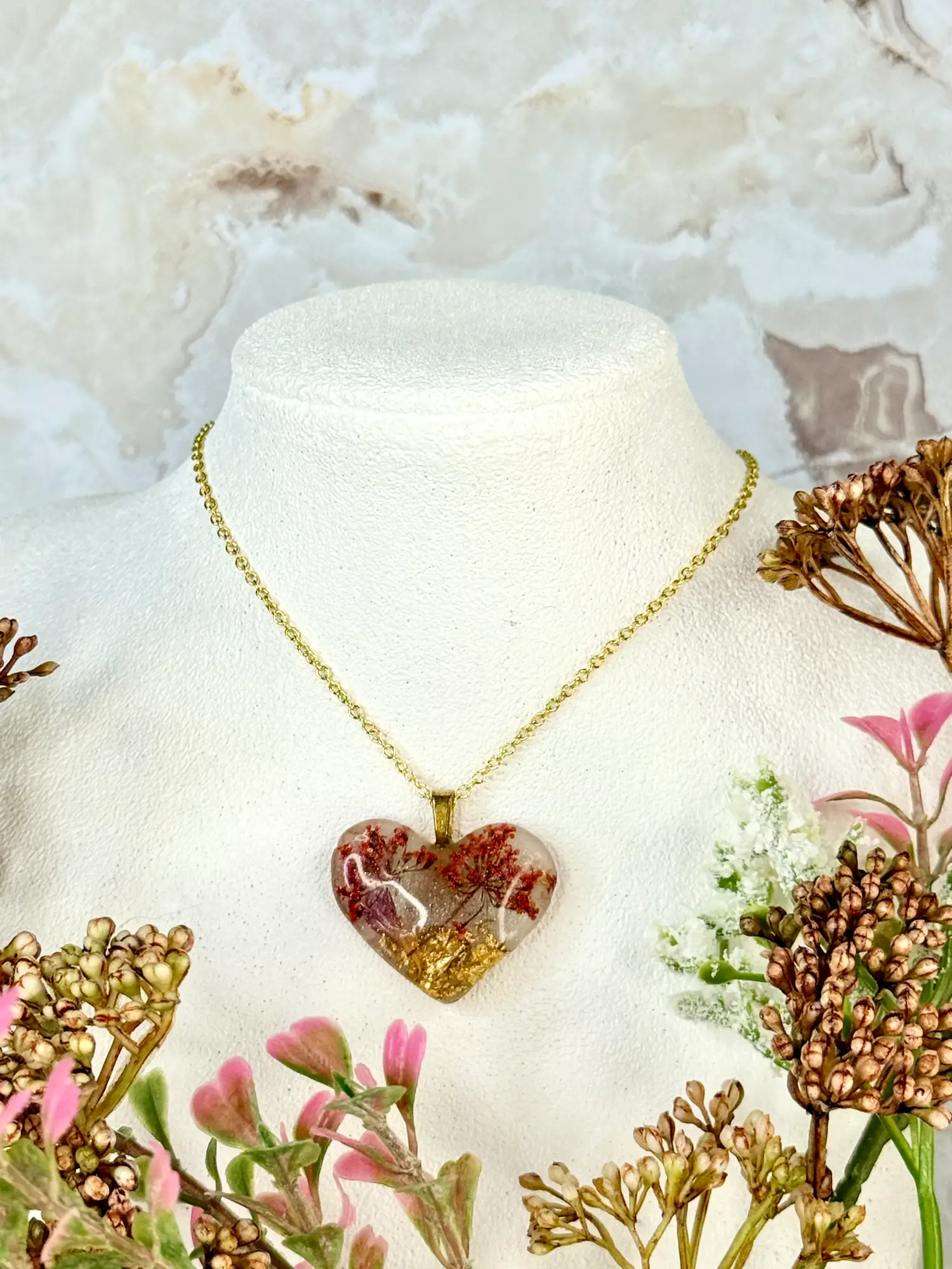 Heart Pendant -- Tiny bouquets of pink flowers set into gold flakes makes for the representation of two cherry trees set into a golden field. Shimmering flecks around the landscape make for a fantasy landscape, somewhere between winter and spring. Made of resin.